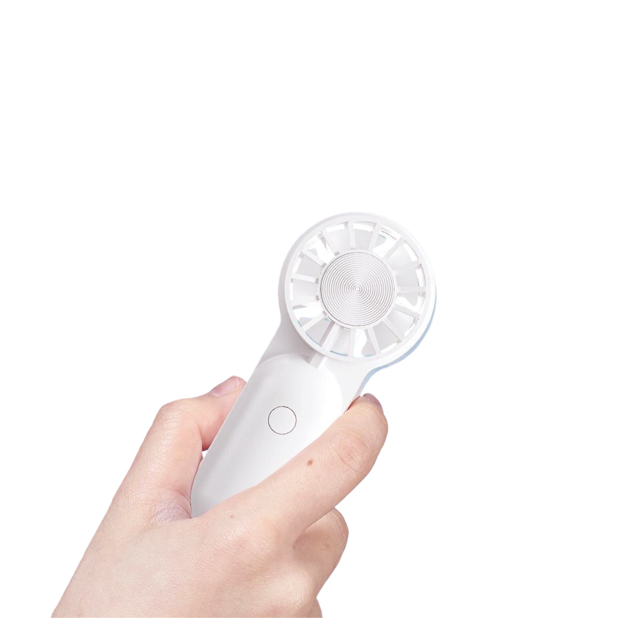 A mini portable handheld fan in white, held in a hand, featuring a circular fan design and a button.
