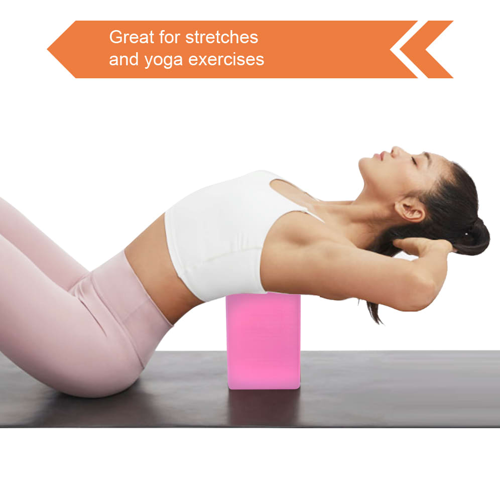 A pink EVA yoga block placed on a mat, used for stretching and yoga exercises. A person performs a pose with it.