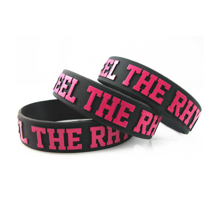 Three embossed black silicone wristbands featuring pink lettering and a logo.