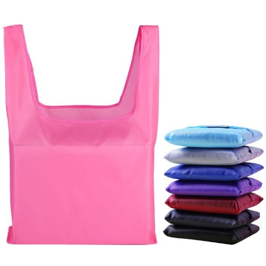 A pink reusable foldaway shopping bag sits alongside folded bags in various colours, including blue, purple, and black.