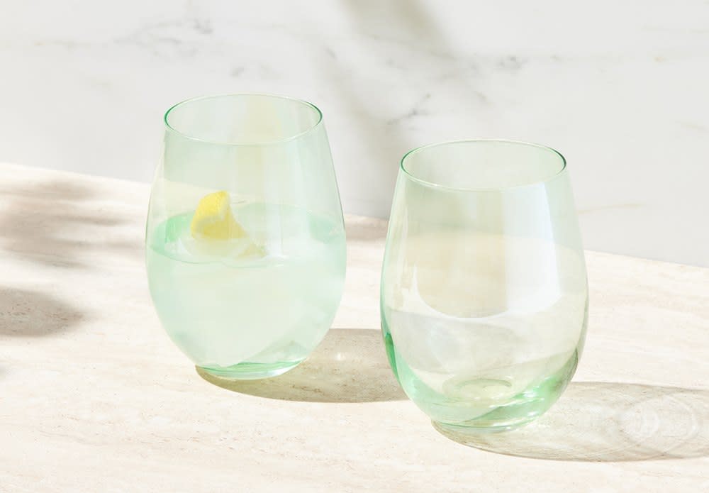 A set of two stemless wine glasses in light green, showcasing one filled with a drink and a lemon slice.