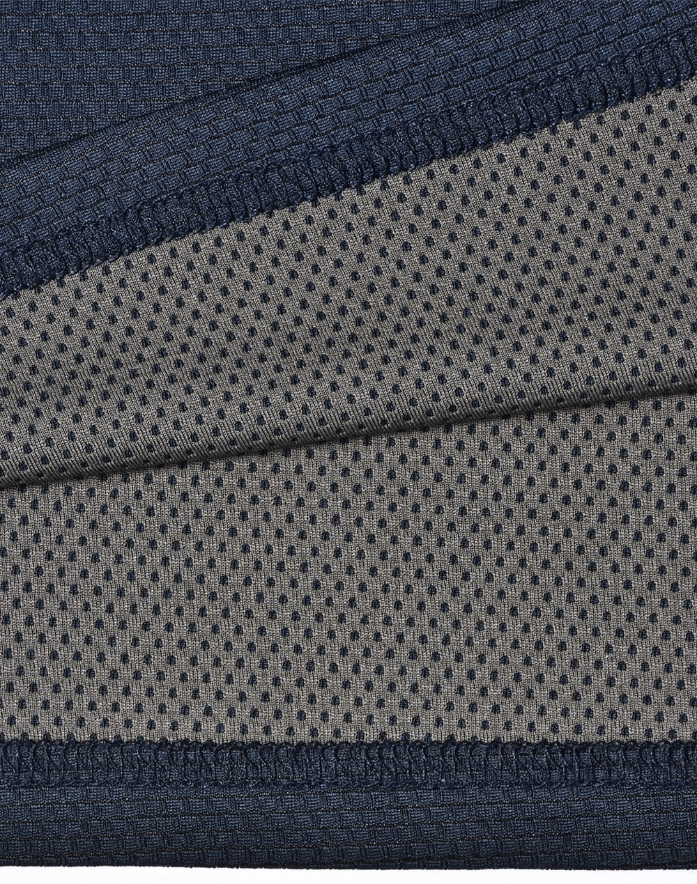 A close-up of a two-tone polo shirt featuring a navy blue top section and a grey, dotted underlay. The fabric is textured and breathable.