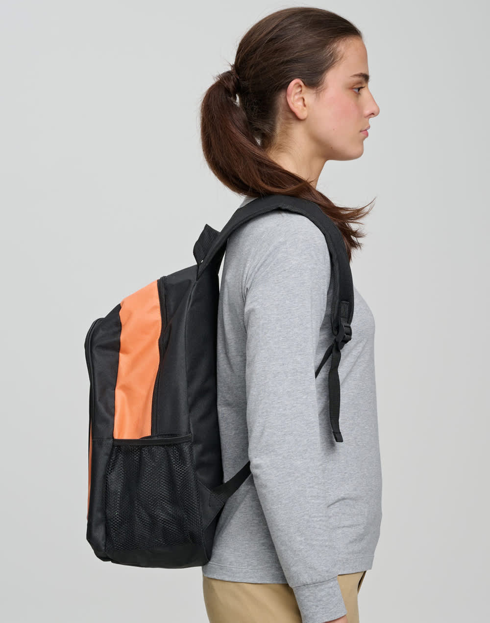 A black backpack with an orange stripe worn by a woman, featuring a logo on the front.