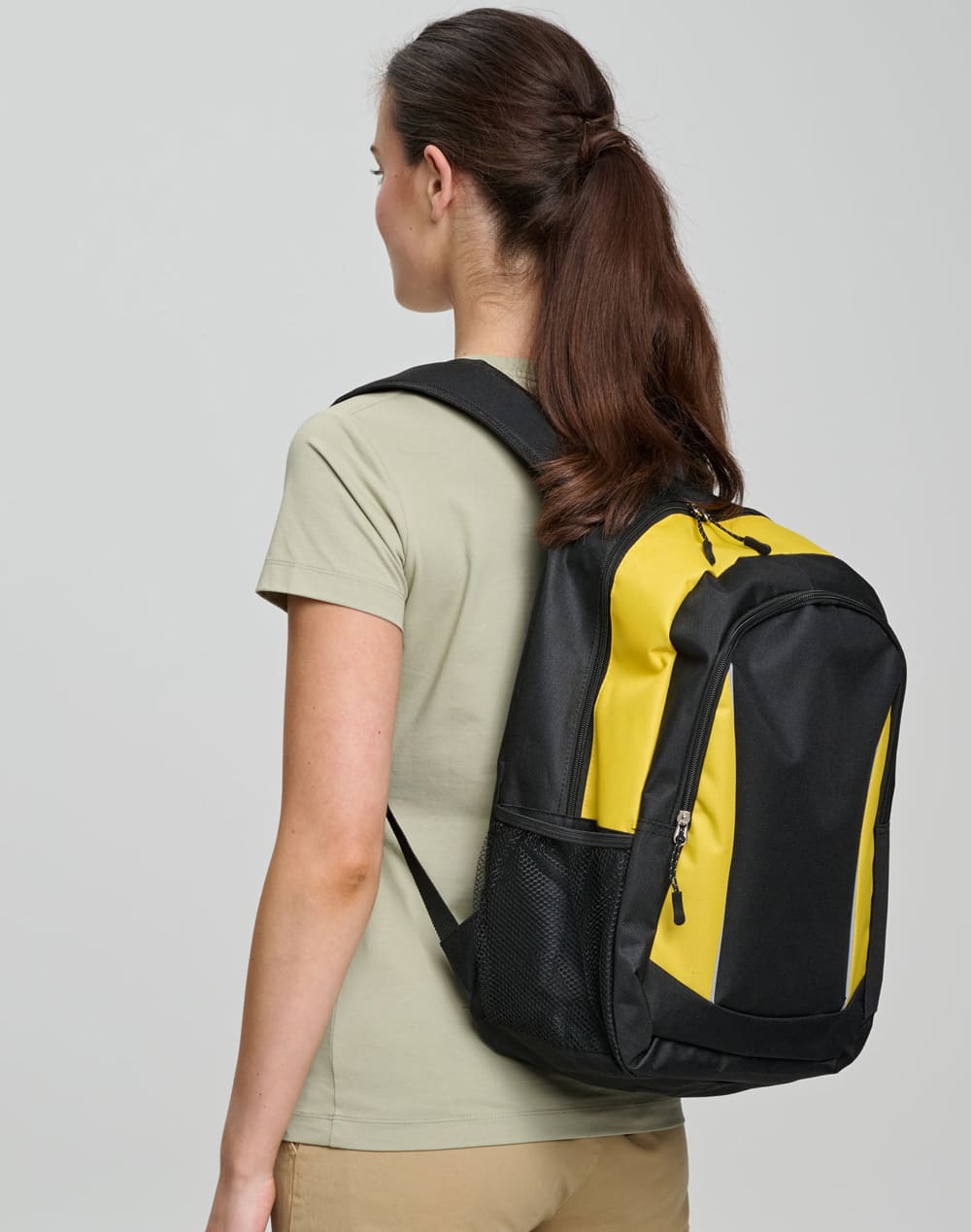 A black and yellow backpack is worn on the back of a person facing away from the camera. The backpack has a logo.