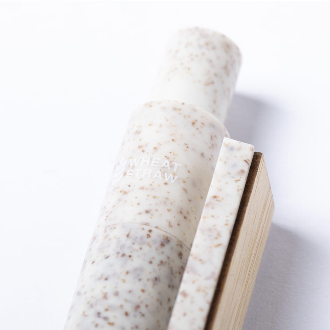 A wooden pen with a speckled white and beige design, resting next to a wooden block, features a logo.