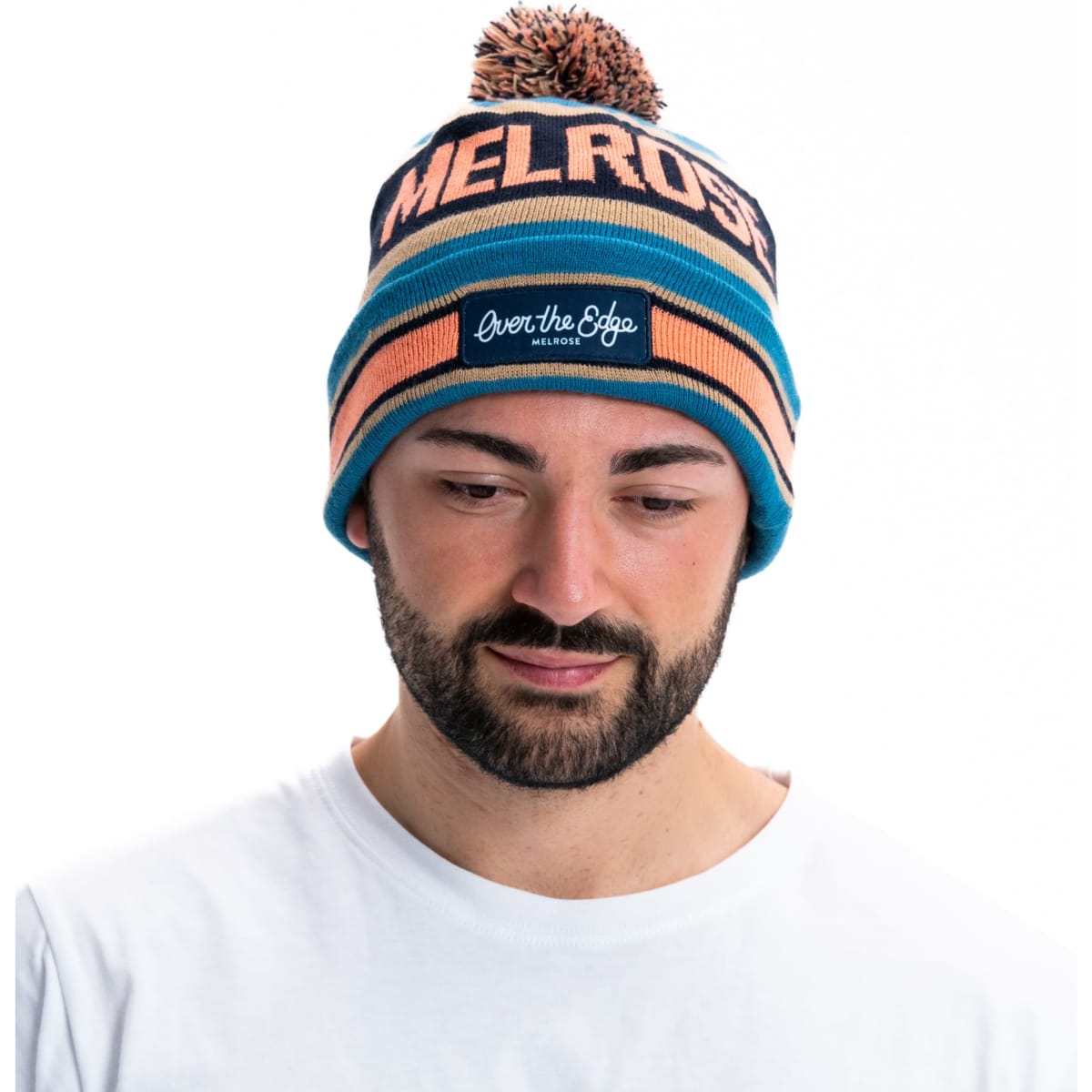 A blue and orange striped beanie with a pom pom on top, featuring a logo on the front.