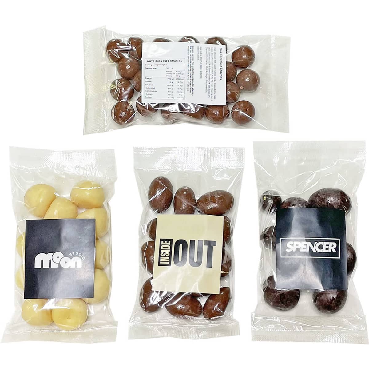 Four clear bags filled with various chocolate treats: dark chocolate, milk chocolate, and white chocolate varieties. Each bag has a logo.