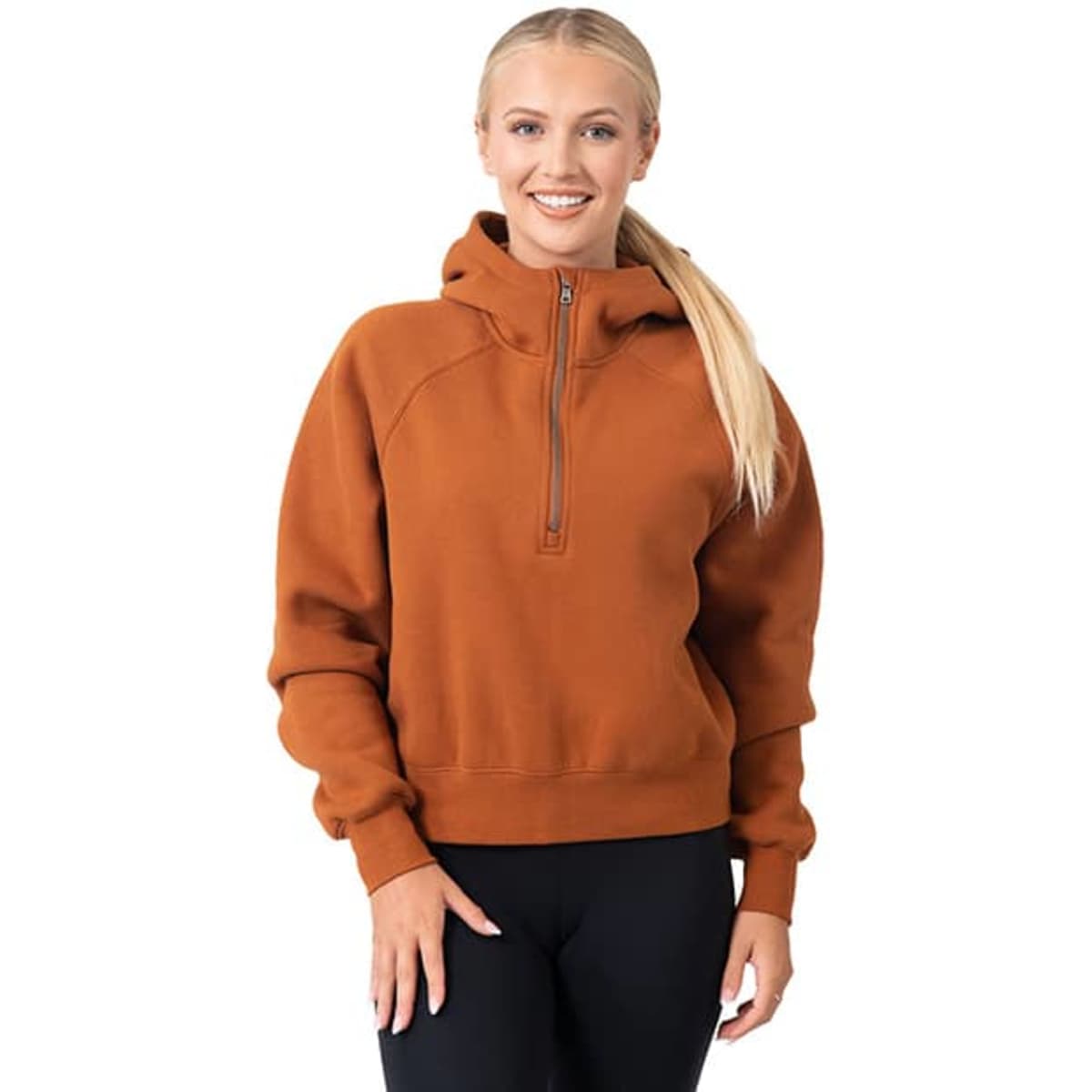 A woman wearing a rust-coloured half-zip jumper with a hood, featuring a slight relaxed fit and long sleeves.