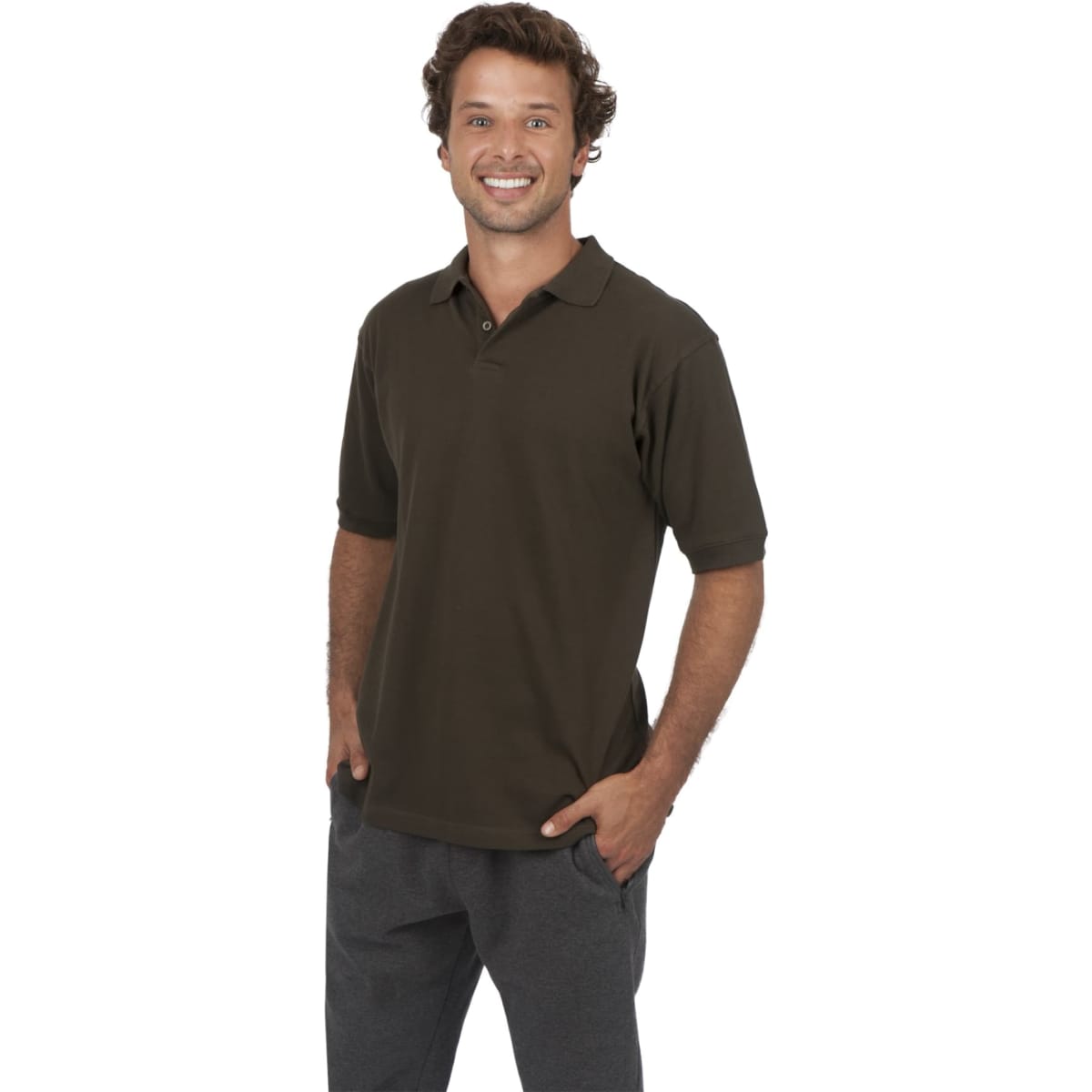 A man wearing a dark olive green cotton polo shirt, standing with hands in pockets and smiling. The shirt has a logo.