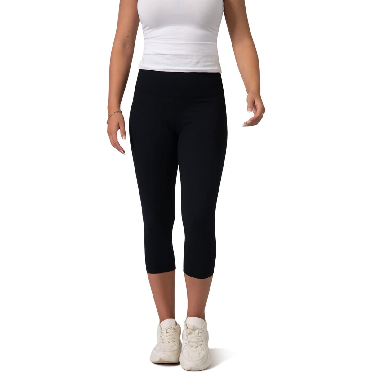 Black high-rise 3/4 leggings worn by a model with a white top and white sneakers. The leggings feature a simple design.