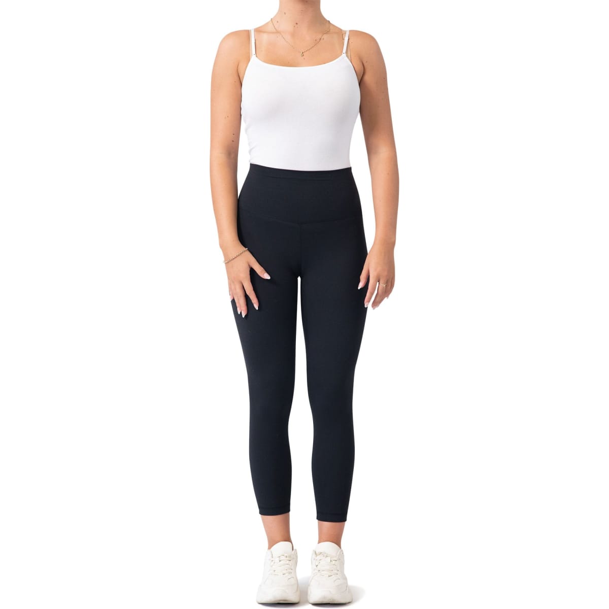 High rise full-length leggings in black, paired with a white tank top and white sneakers. Features a logo on the waistband.