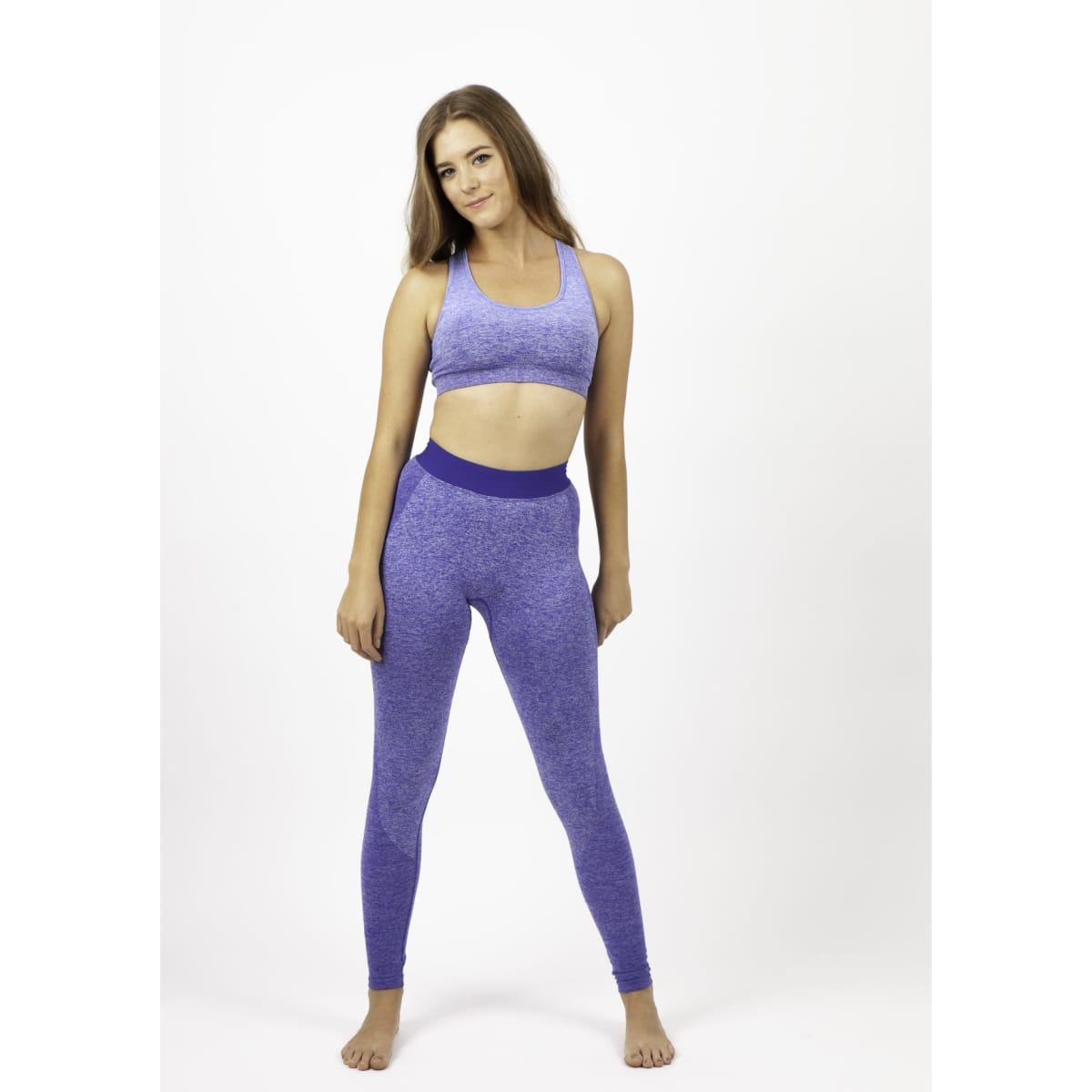 A model wearing seamless leggings in a vibrant purple hue, paired with a matching crop top. The image features a logo.