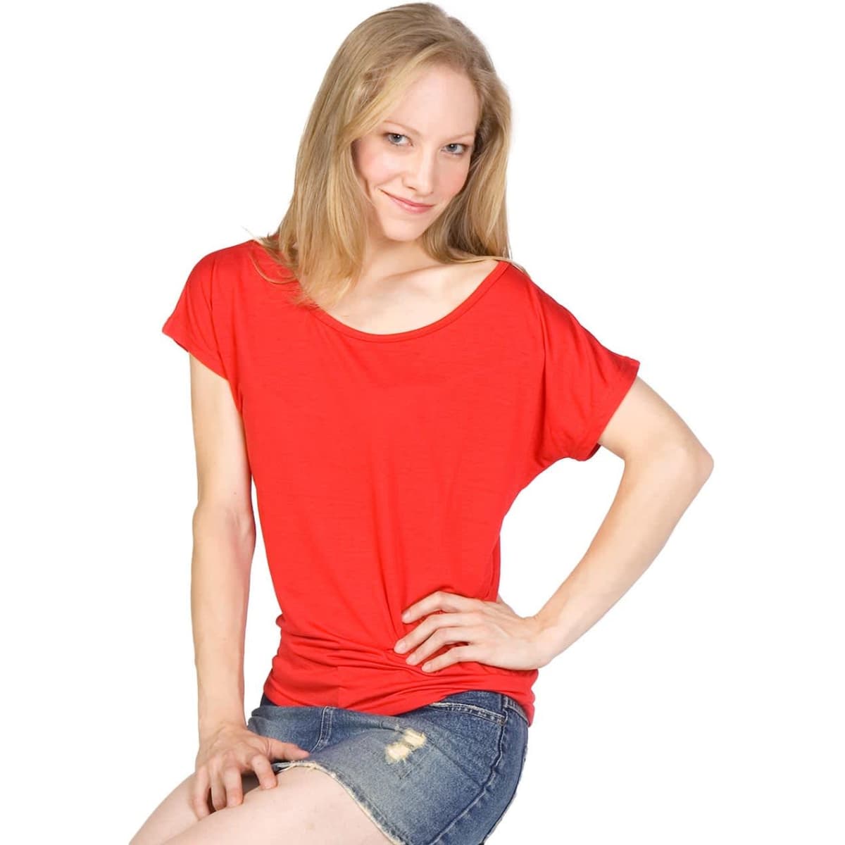 A model poses on a stool wearing a red bat wing T-shirt, denim shorts, and black high heels. The image includes a branding logo.