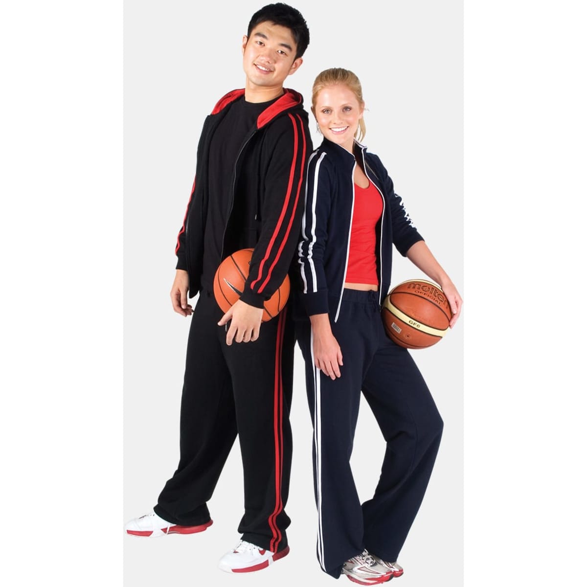 A pair of models wearing women's striped track pants in navy blue and red, each holding a basketball.