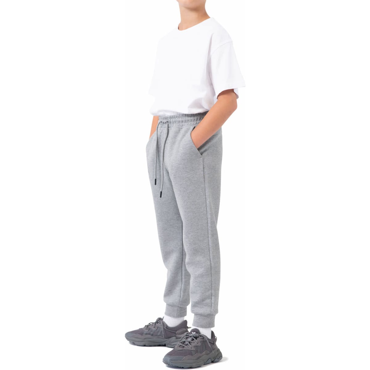 Grey three-layer cotton track pants with pockets, worn by a child in a white t-shirt and athletic shoes.
