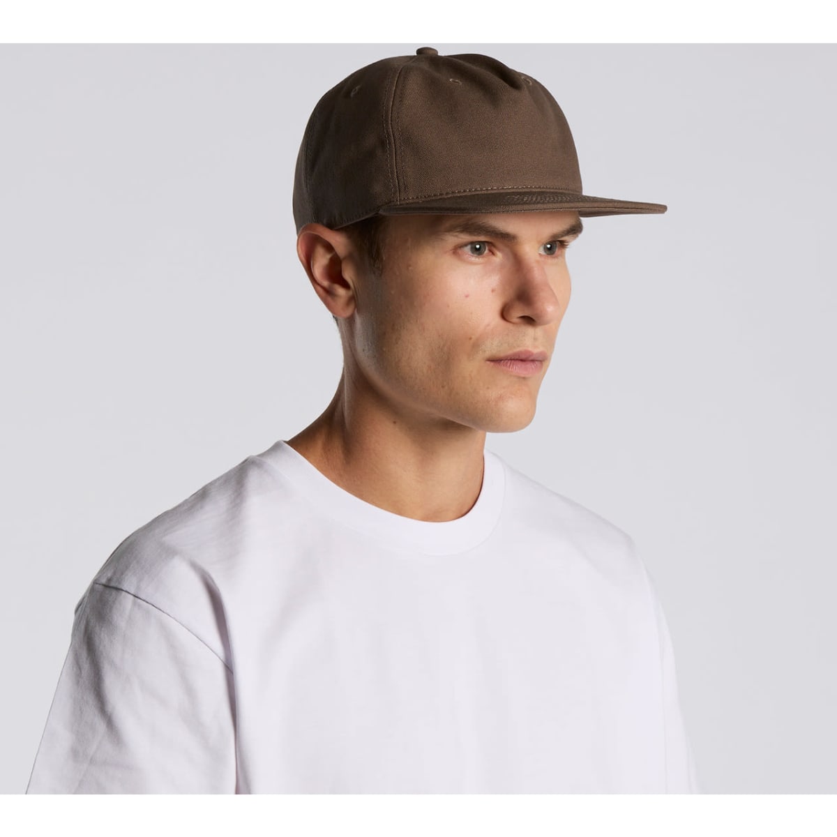 A man wearing a brown cap, facing slightly to the right. The cap has a simple design and a straight brim.