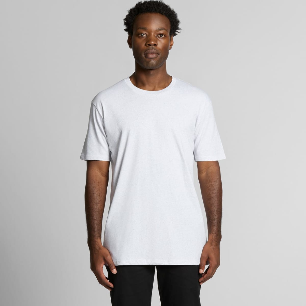 A plain white t-shirt with short sleeves, featuring a logo on the front, modelled by a person standing against a neutral background.