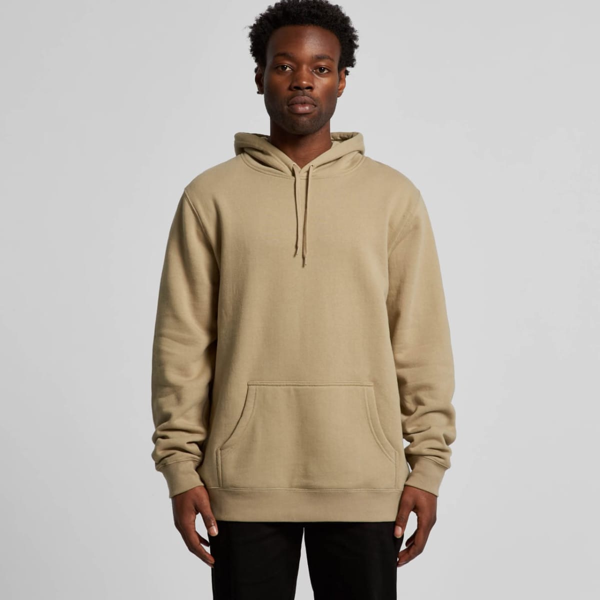 A beige hoodie with a front pocket and drawstring hood, displayed on a model. It features a brand logo.