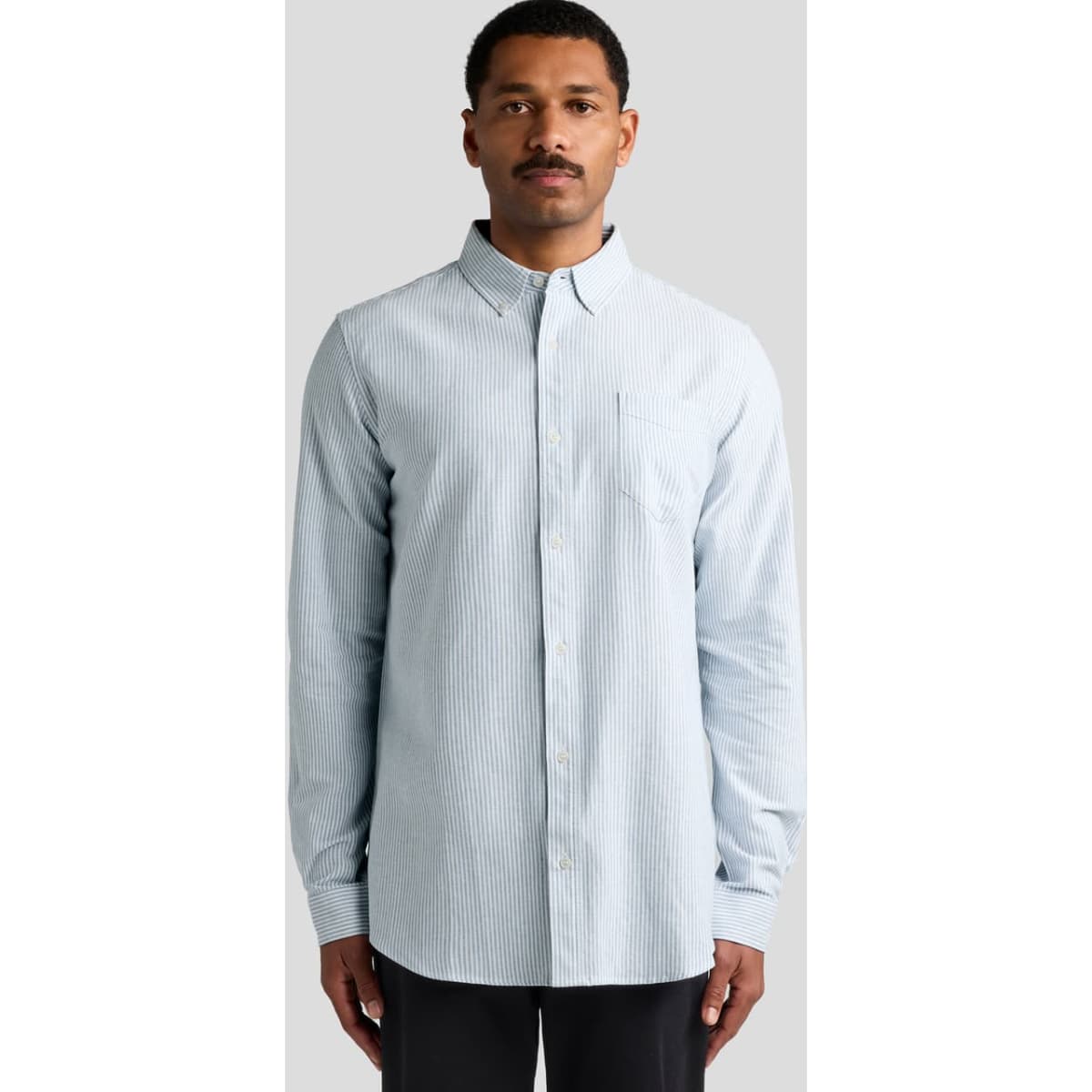 A button-up shirt in light blue with white stripes, featuring a collar and a pocket. It has a logo on the chest.