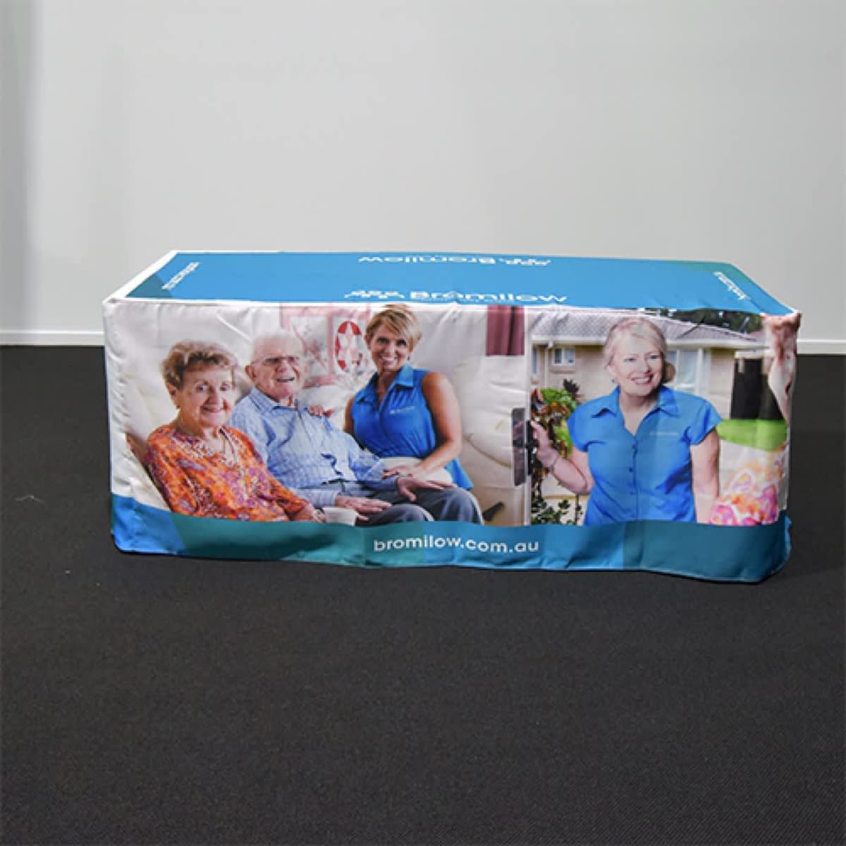 A fitted table cover featuring various images of people, predominantly in blue and white colours, and includes a logo.