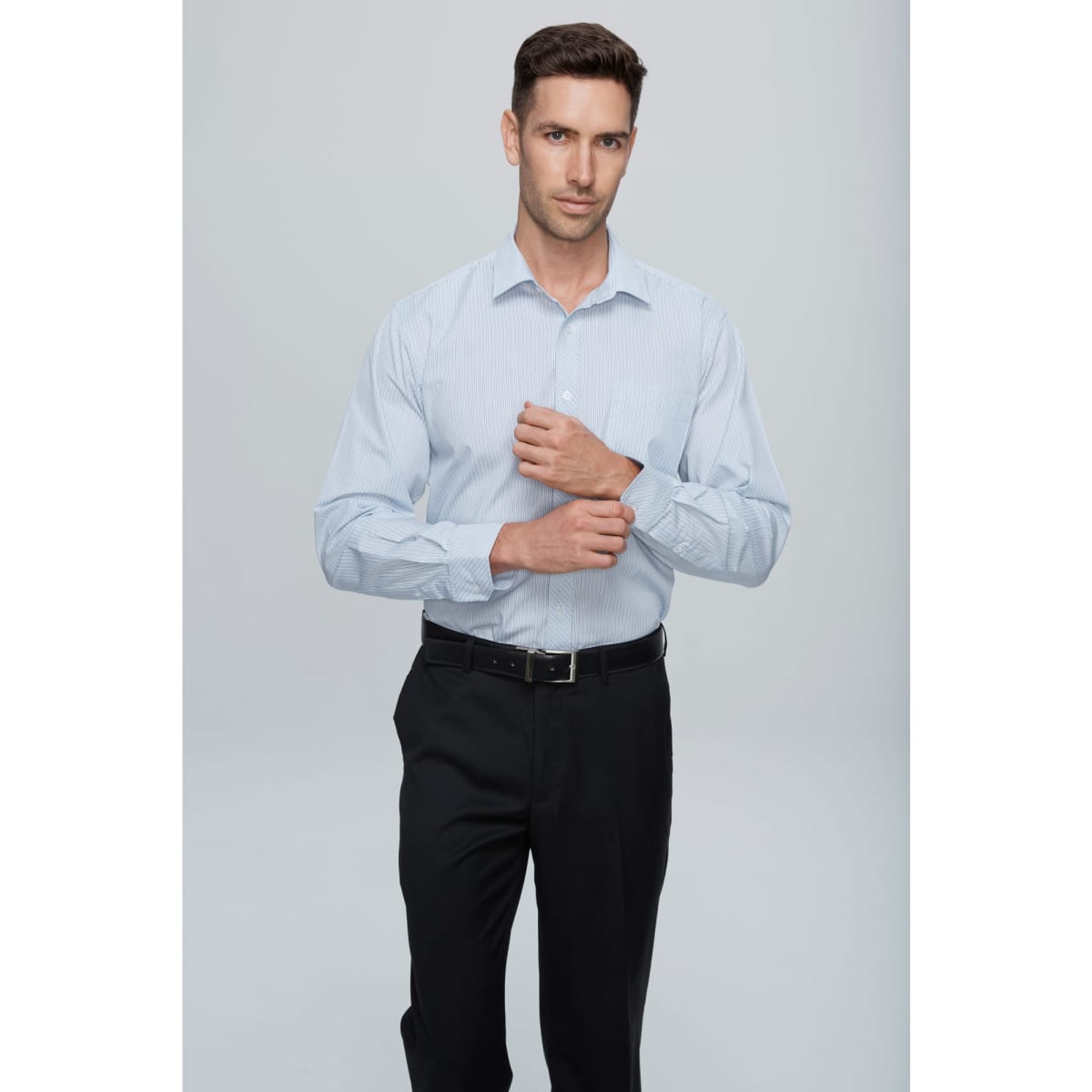 A long sleeve button-up shirt in light blue, featuring a collar and a logo, worn with black trousers.