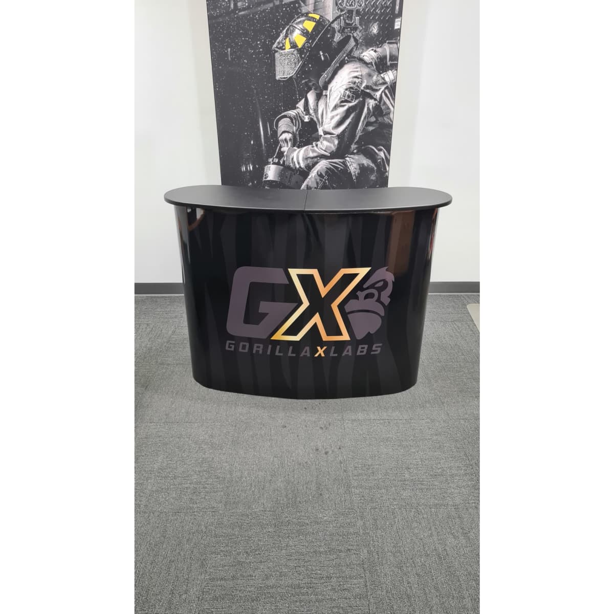 A black promotional table with a curved design features a logo and a smooth glossy finish.