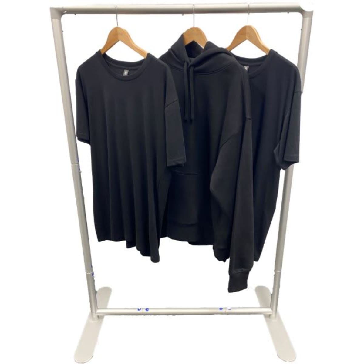 A transportable clothes rack displaying three black garments: a T-shirt, a hoodie, and a short-sleeve shirt.