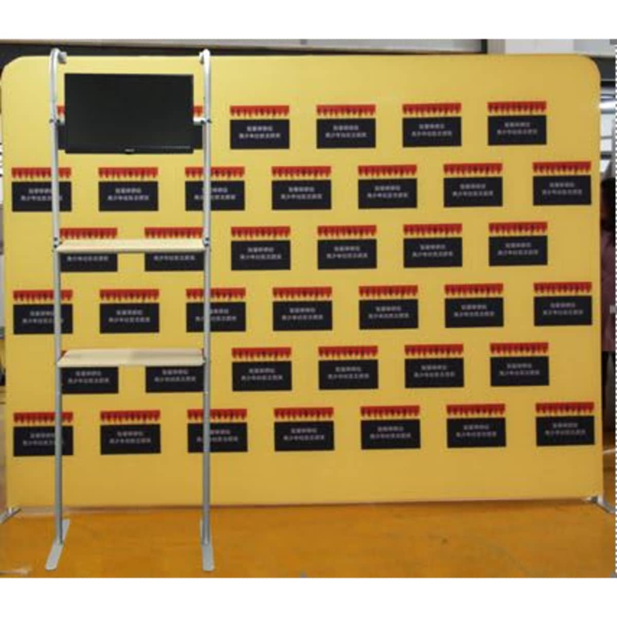 A shelving unit with a yellow background and a screen attached, featuring dark panels without visible text.