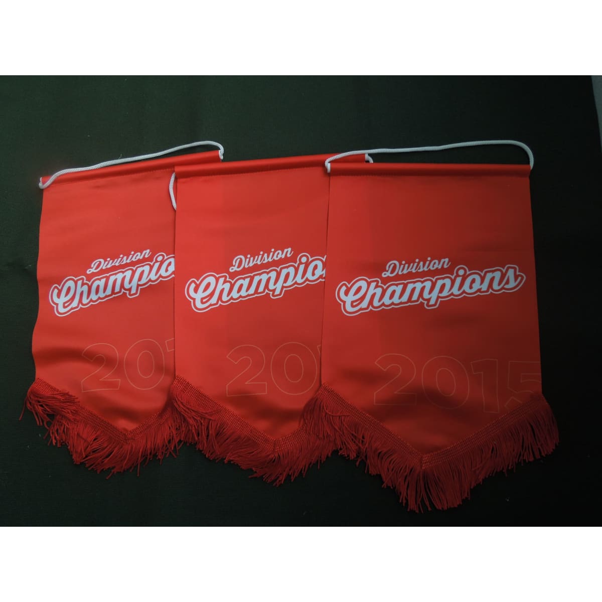 Three red pennants with white text and fringes, featuring a logo and a design indicating division champions.