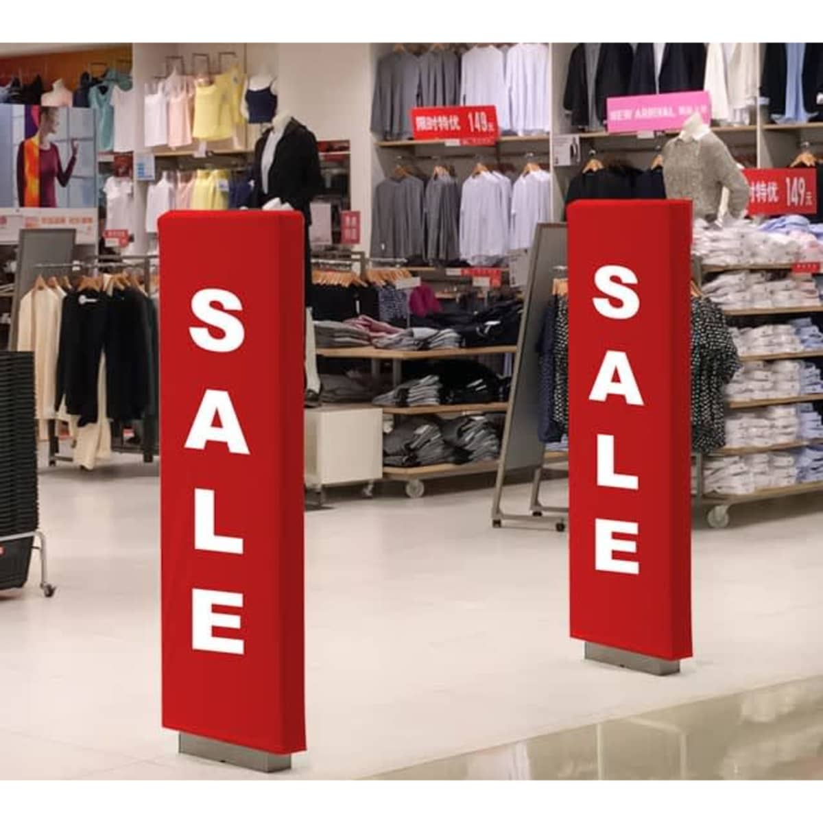 Two tall red security gate covers with white text, displayed in a retail clothing store.