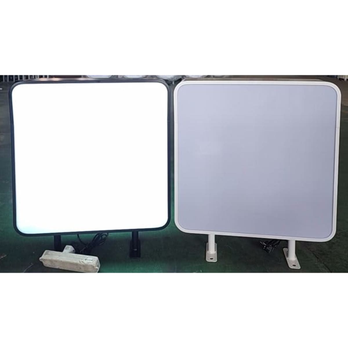 Two wall mount light boxes, one with a black frame and illuminated, the other with a white frame and unlit.