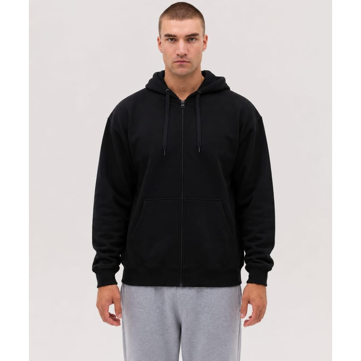 A black zip hoodie with a front pocket and a drawstring hood, modelled by a person against a neutral background.