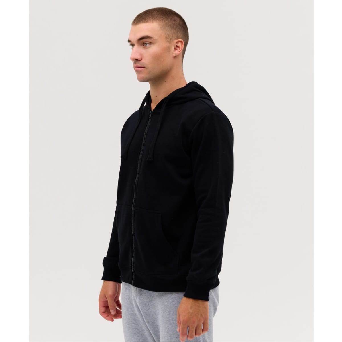 A black zip-up hoodie featuring a hood, displayed on a model against a plain background.