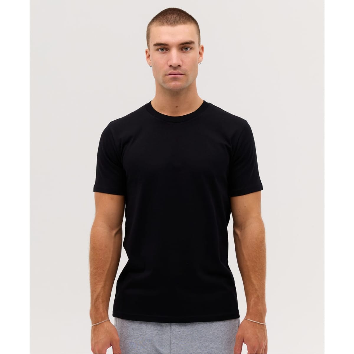 A black classic tee is displayed on a model, showcasing a fitted design and short sleeves.