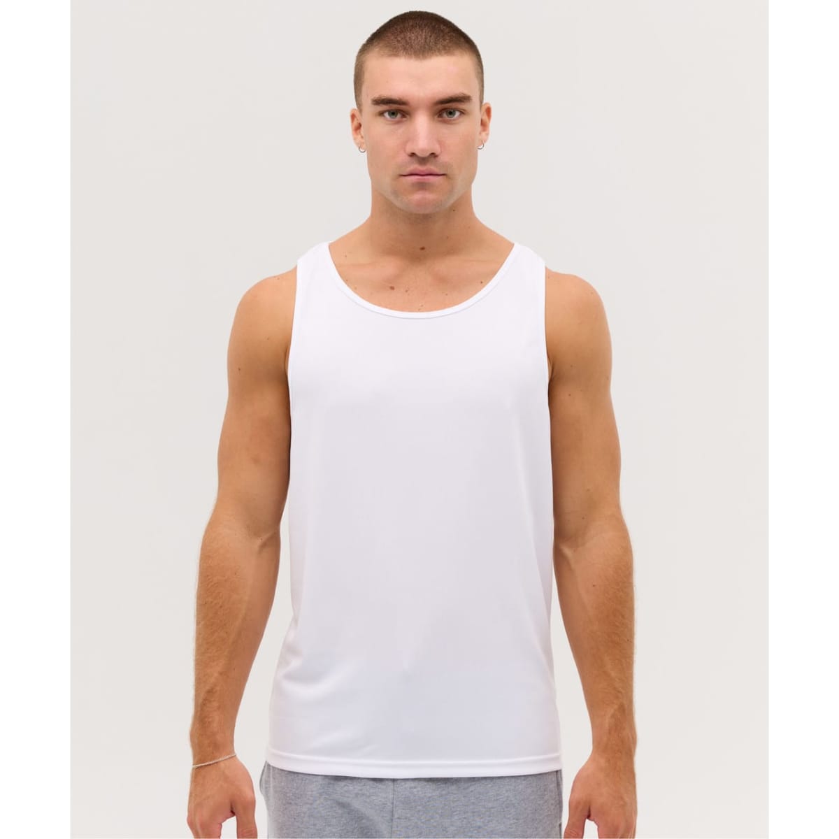 A white singlet shirt displayed on a model with short hair. The shirt has a branding logo.