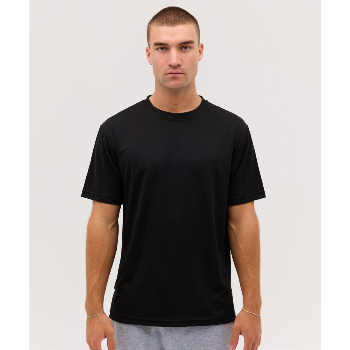 A black t-shirt displayed on a model, featuring short sleeves and a round neckline. It has a minimalistic design and a logo.