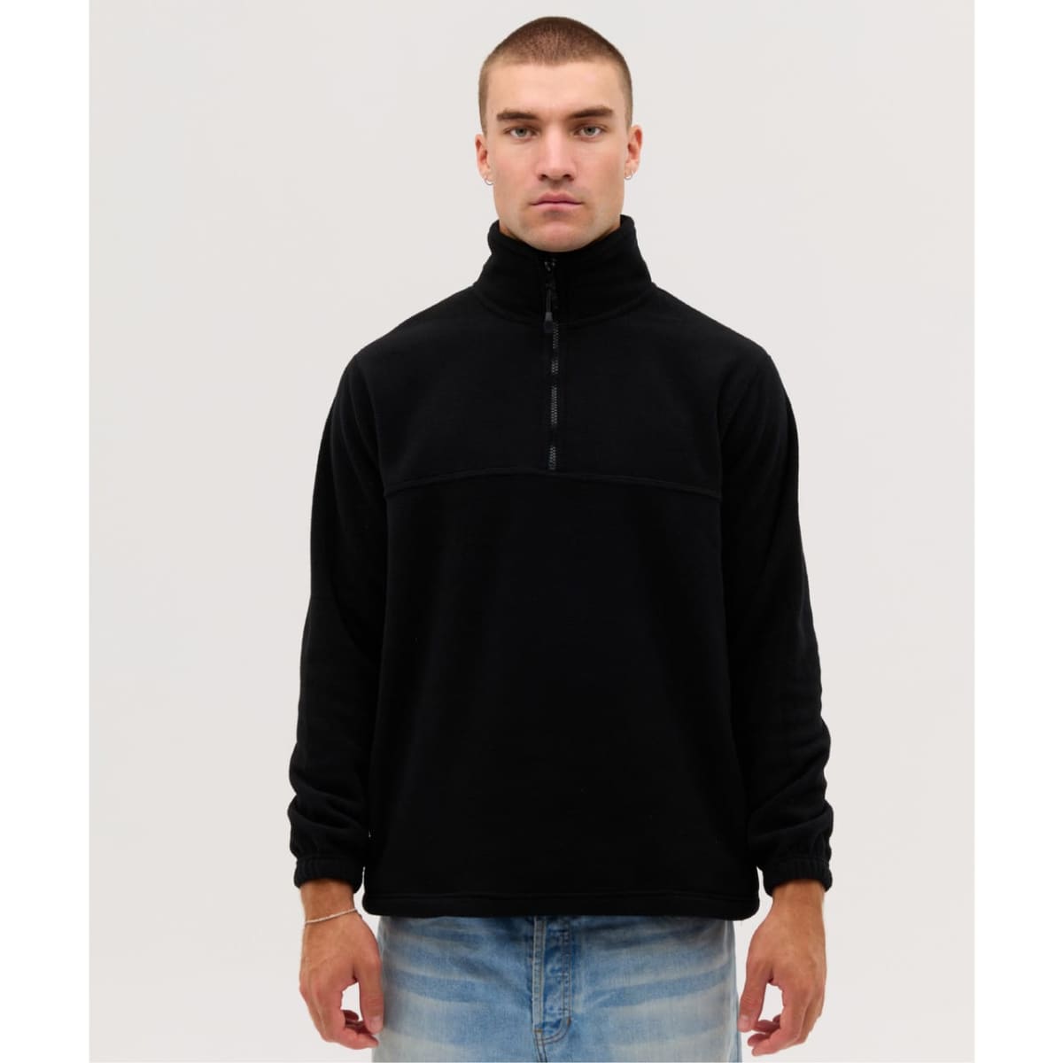 A black Everest Polar Fleece 1/4 zip jacket displayed on a model wearing blue jeans. Features a front zipper and high collar.