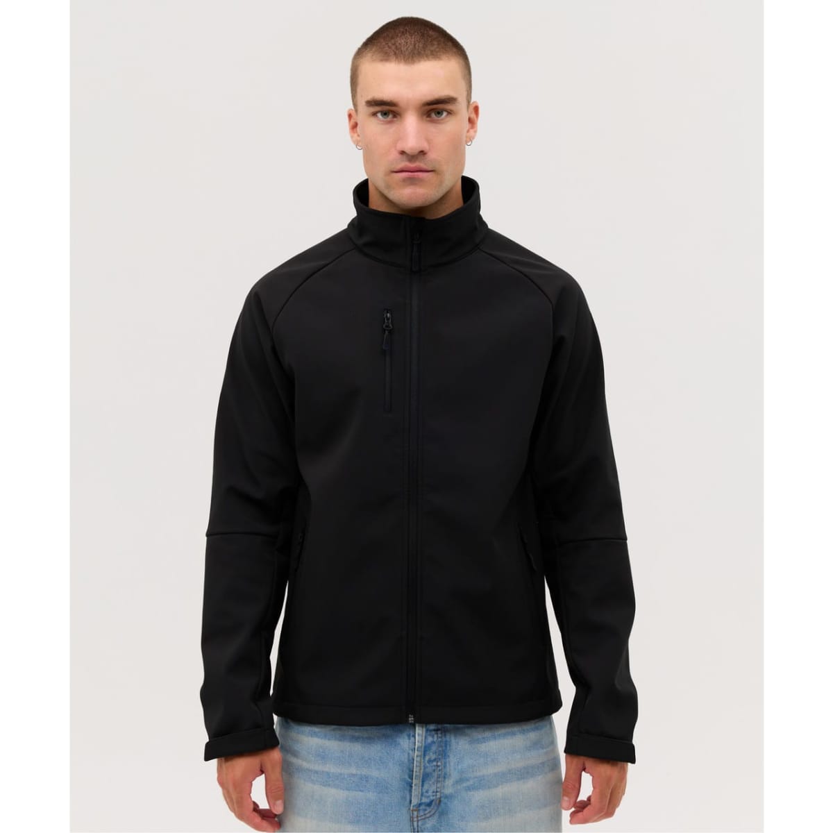A soft shell jacket in black, featuring a zip front and a high collar, worn by a model. It has a logo on the chest.