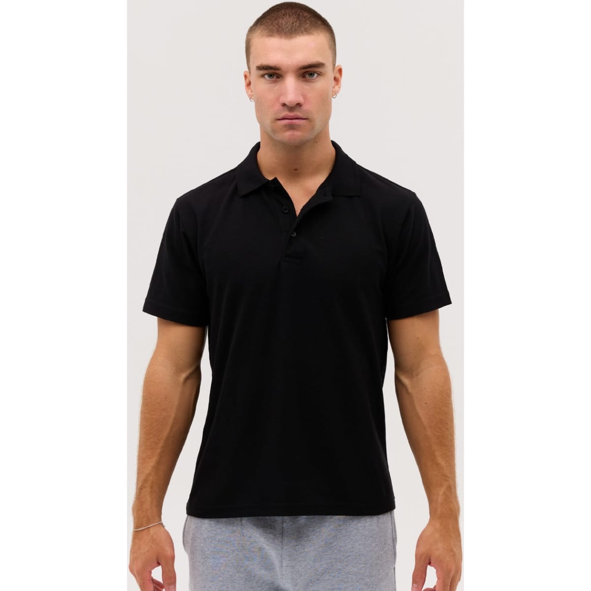 A black polo shirt with a collar and short sleeves, featuring a logo on the chest.