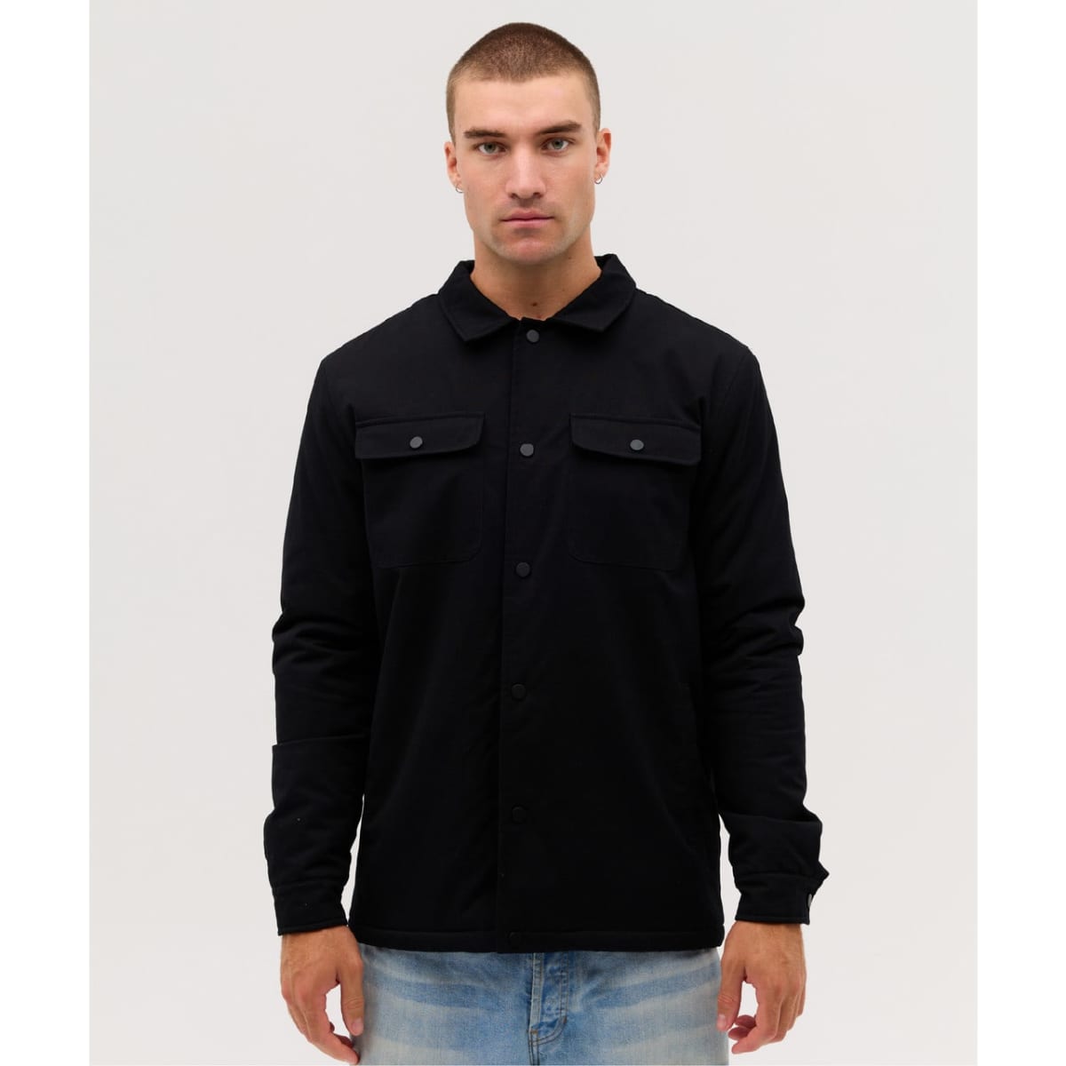A black soft shell jacket with two chest pockets and buttons, worn by a model against a neutral background.