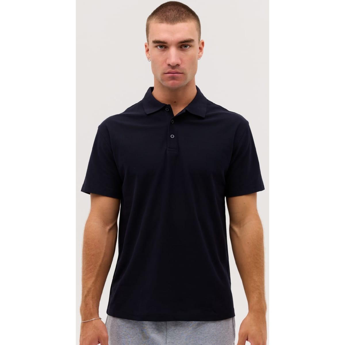 A navy polo shirt features a collar and short sleeves, with a logo on the chest. Ideal for casual wear.