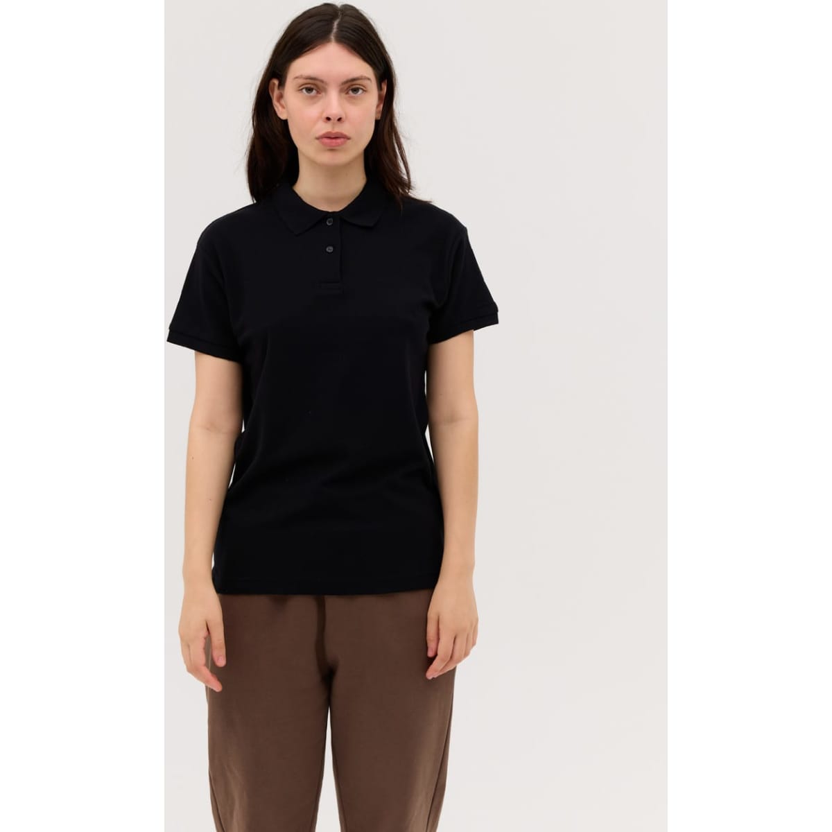 A black women's polo shirt with a collar, short sleeves, and a logo on the chest, displayed on a model.