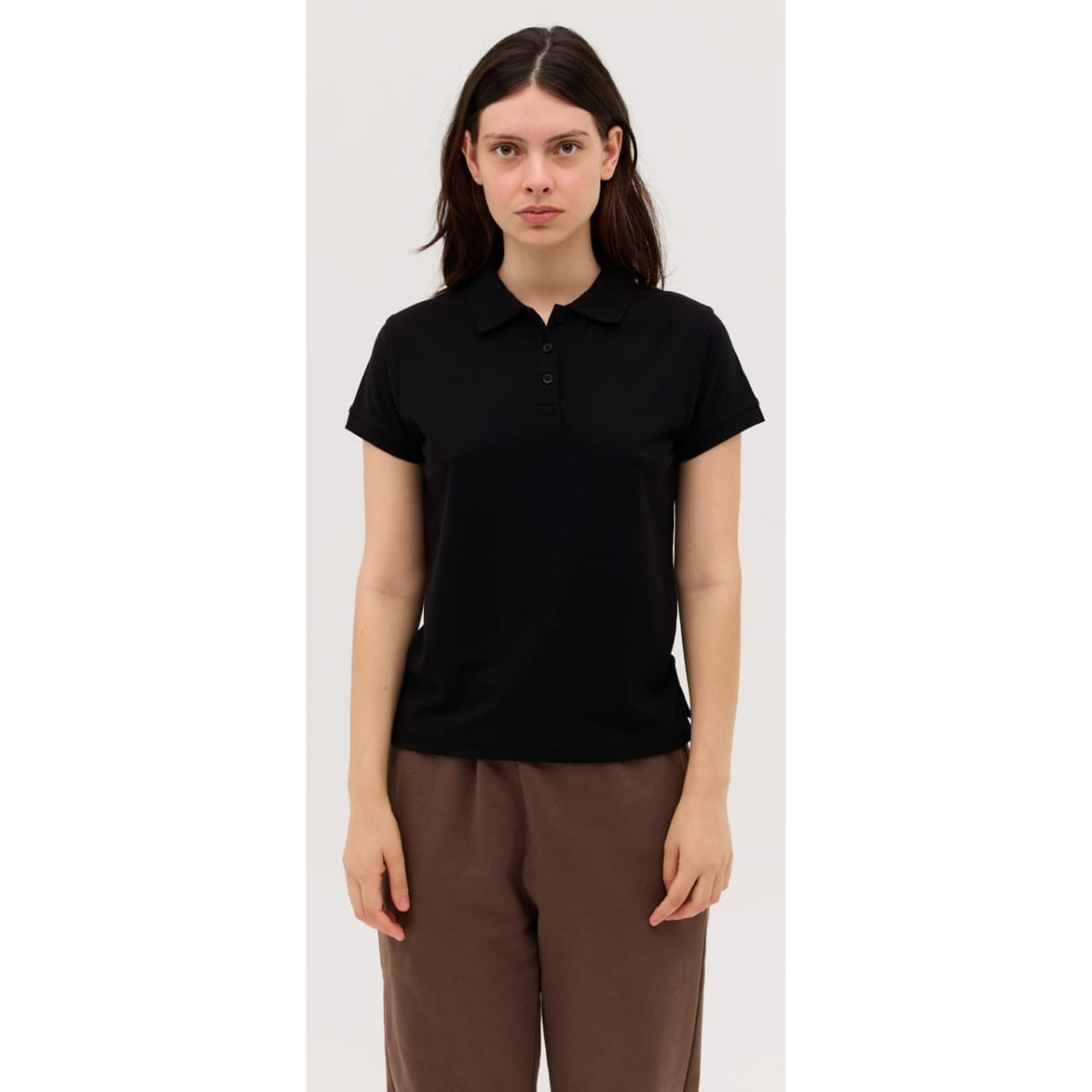 A black women's polo shirt with a collar, featuring a logo on the fabric, styled with short sleeves.