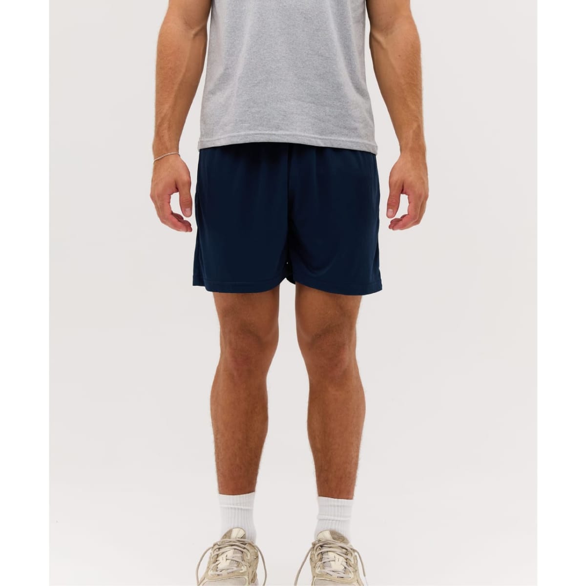 A model wearing navy sports shorts paired with a grey T-shirt and light-coloured sneakers.