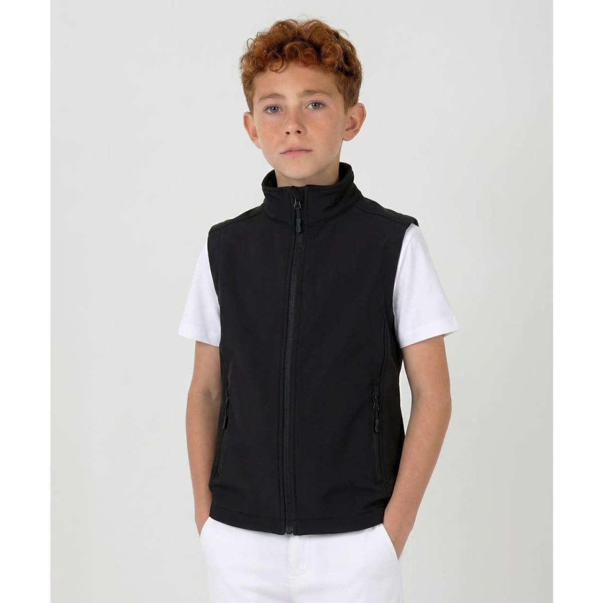 A black softshell vest for youth featuring a zip front and side pockets, worn over a white t-shirt.