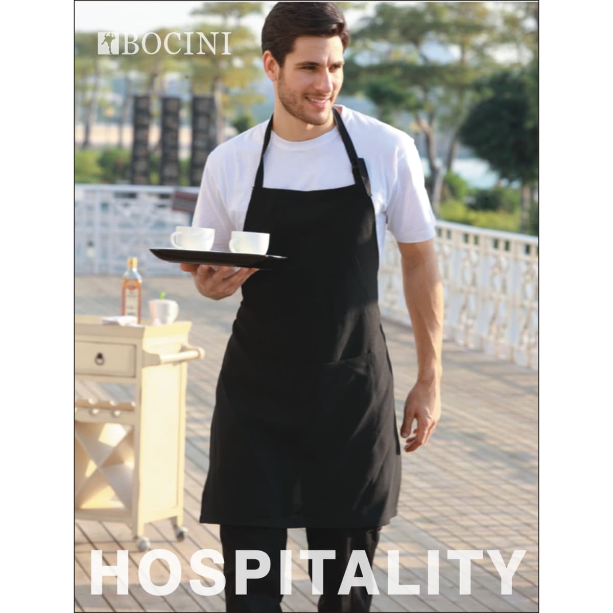 A man wearing a black cotton drill full bib apron with a pocket, holding a tray with two cups.