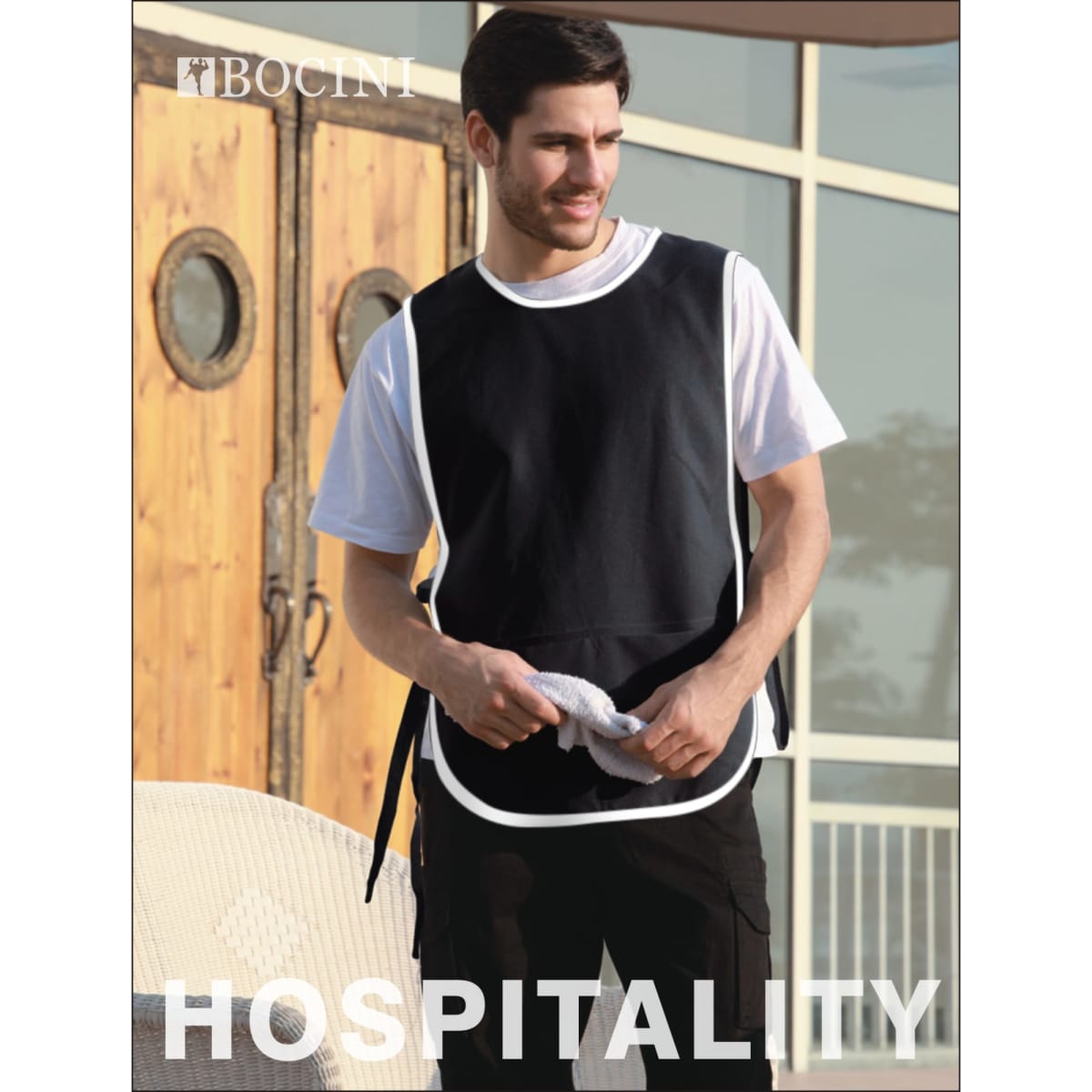 A black polyester drill popover apron with a pocket, worn by a man, featuring a logo.