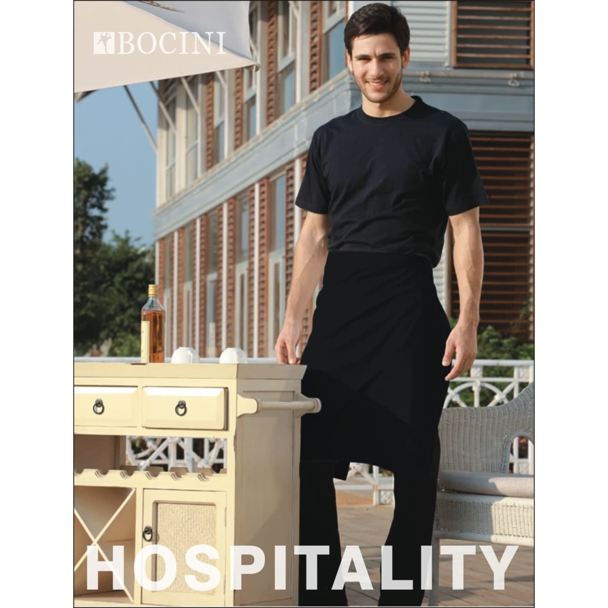 A man wearing a black polyester drill half apron stands by a table outside, featuring a logo on the apron.