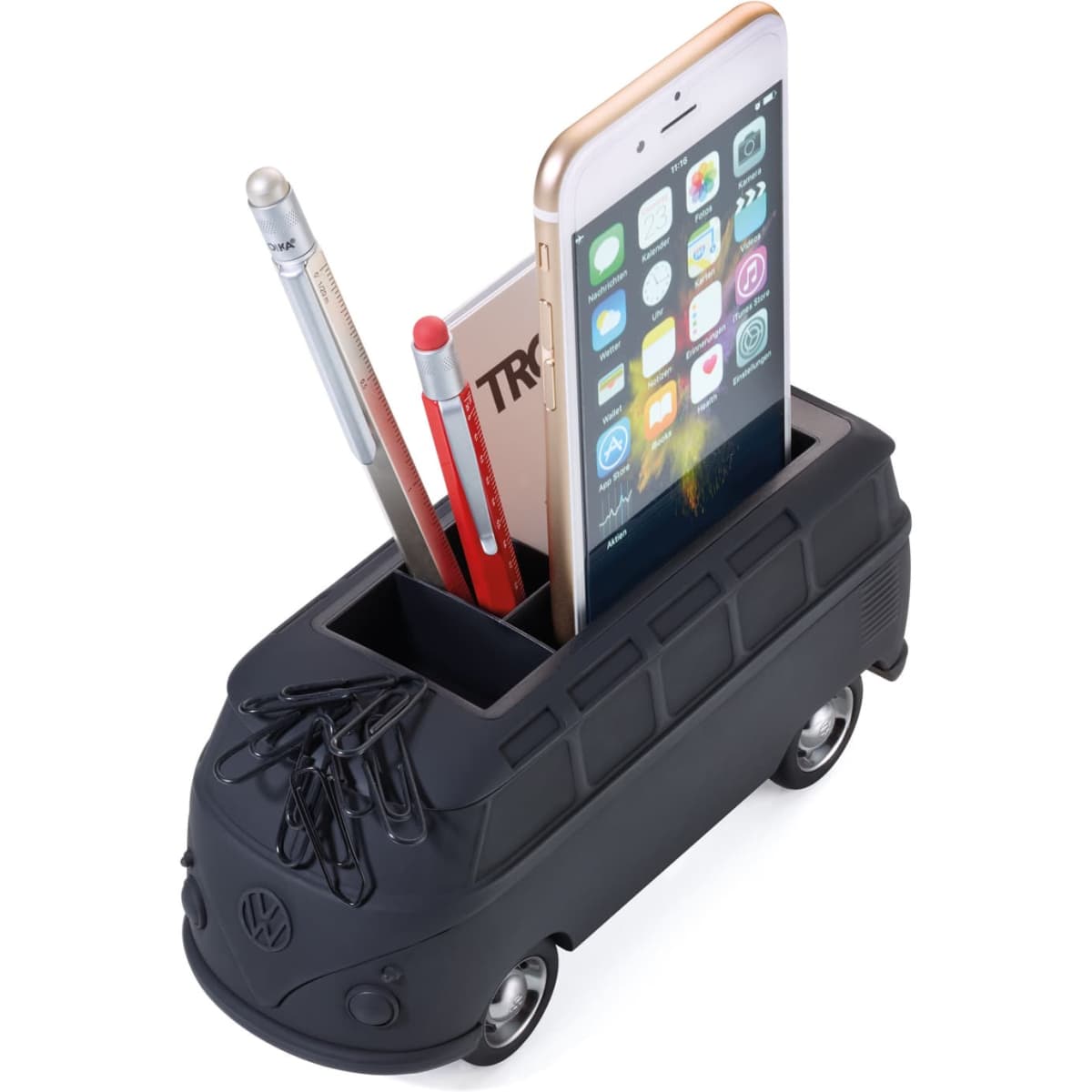 A black Volkswagen bus-shaped business card holder with pens and a smartphone. Features rolling wheels.