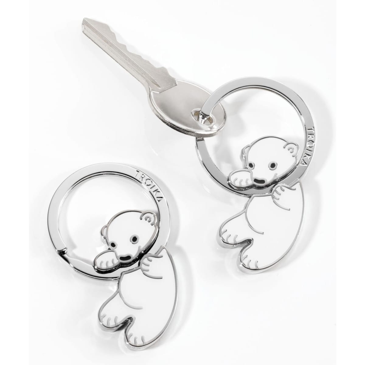 A silver keychain featuring a polar bear design, attached to a standard key.